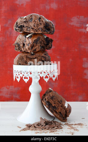 Stapel von Schokolade Obst Brötchen auf weißen Kuchen stehen auf weißen shabby chic Holztisch mit roten Hintergrund Hintergrund. Stockfoto