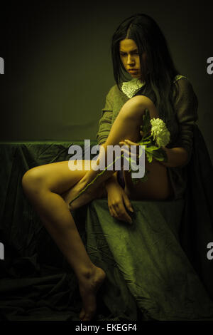 Junge Brünette Frau mit weißen Chrysanthemen Porträt. Dunkle Farben. Stockfoto