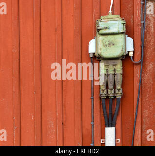 Retro-Stil der Stromkreise, Steckdosen und Anschlussdosen montiert auf einer roten Wand aus Holz Stockfoto