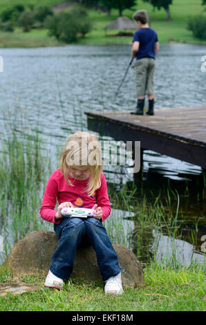 Junge Mädchen spielen Computerspiel in der Natur Stockfoto