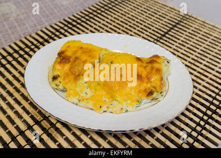 Kabeljau-Filets mit Käse-Sauce auf einem Teller Stockfoto