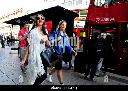 London, England, Vereinigtes Königreich. Zwei junge Frauen vorbei an einer Bushaltestelle Stockfoto