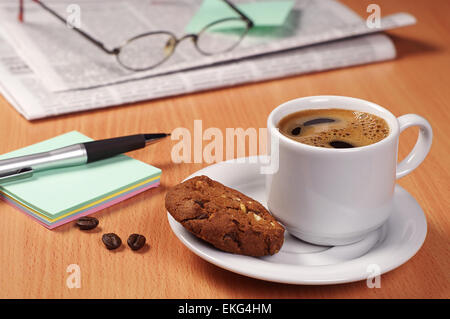 Tasse heißen Kaffee mit Cookie, Zeitung und Hinweis auf Holztisch Stockfoto