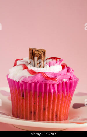 Raspberry Ripple Cupcake mit Schokolade Flocken auf Herz Teller setzen auf rosa Hintergrund Stockfoto