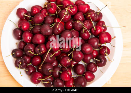 Frische, rote Kirschen auf einem weißen Teller Stockfoto