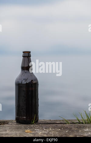 Geöffnete 500ml Flasche Bier auf alten rustikalen Holz in der Natur Stockfoto