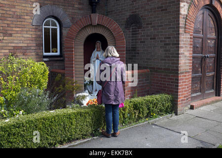 eine Frau betet zu einer Statue der Maria, der Mutter Jesu außerhalb St. Catherines römisch-katholische Kirche in Didsbury, manchester Stockfoto