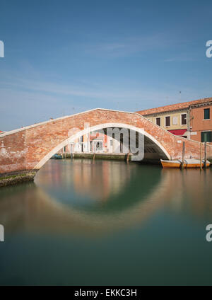 Eine alte Brücke in Murano, Italien, mit einer langen Belichtungszeit aufgenommen. Reflexionen im Wasser zu sehen Stockfoto