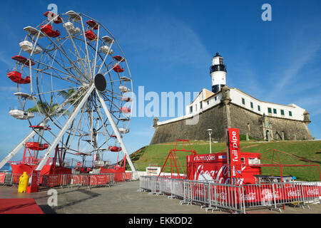 SALVADOR, Brasilien - 11. März 2015: Ein Riesenrad von Coca-Cola gesponsert dominiert den Blick auf den Leuchtturm von Barra. Stockfoto