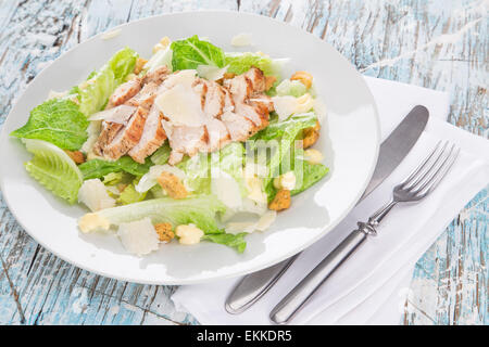 Caesar Salat mit Hühnchen und Grüns auf Holztisch Stockfoto