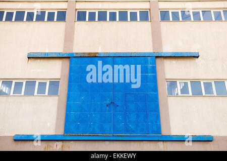 Industrielle Gebäude-Fassade mit großen blauen geschlossenen Metalltor, Foto Hintergrundtextur mit Perspektive-Effekt Stockfoto