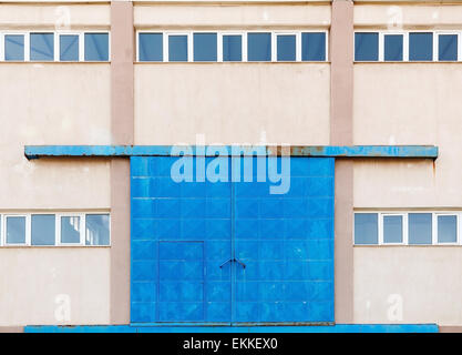 Industrielle Gebäude-Fassade mit großen blauen geschlossenen Metalltor, Foto Hintergrundtextur Stockfoto
