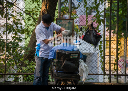 Straßenhändler sind ein alltäglicher Anblick in Asien. Open-Air-Friseur. Stockfoto