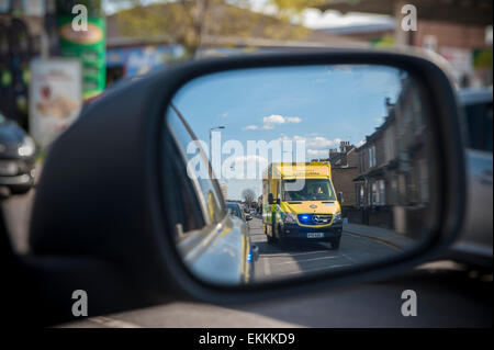 Ein Rennsport-Krankenwagen mit Blaulicht überholt ein Auto, das es in seiner Flügel Spiegel sieht Stockfoto