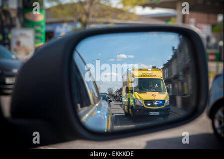 Ein Rennsport-Krankenwagen mit Blaulicht überholt ein Auto, das es in seiner Flügel Spiegel sieht Stockfoto