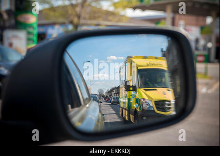 Ein Rennsport-Krankenwagen mit Blaulicht überholt ein Auto, das es in seiner Flügel Spiegel sieht Stockfoto