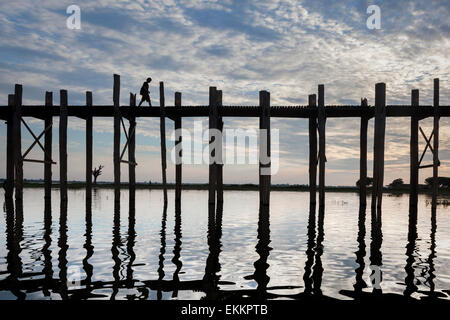 Eine einzelne isolierte Figur, einem westlichen Mann in kurzen Hosen, Fortschritte über U Bein Brücke, selbst die Silhouette, und reflektiert. Stockfoto