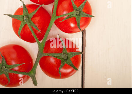 frische Kirschtomaten auf einem Cluster über rustikalen Holztisch Stockfoto