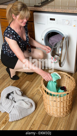 Frau mit Hilfe einer Waschmaschine Trockner Maschine Stockfoto