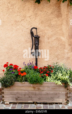 Detail der alten Wasser-Pumpe und Pflanzer-Boxen mit Geranien in Obernai, Elsass, Frankreich Stockfoto