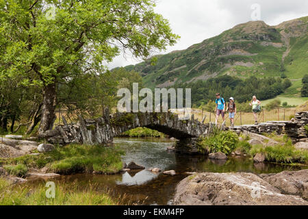 Wanderer kreuz Slater Brücke und den Fluss Brathey im Little Langdale - Lake District, England Stockfoto