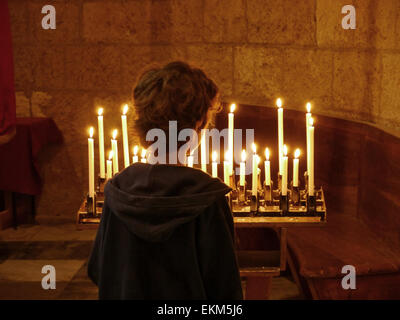 Ein kleiner Junge, der Blick auf einige Kerzen in einer Kirche Stockfoto