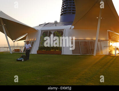 Ein Mann Mähen des Rasens auf dem Deck der Kreuzfahrt Schiff Celebrity Equinox. Stockfoto