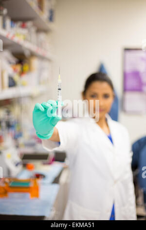 Closeup Portrait, intelligente Wissenschaftlerin im weißen Laborkittel zeigt Nähe Spritzennadel, isoliert Lab background Stockfoto