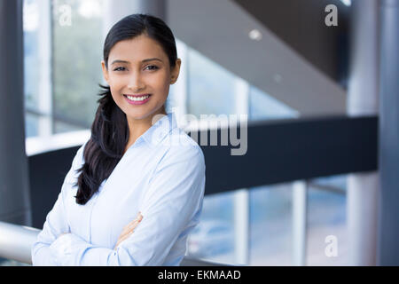 Closeup Portrait, gefaltet junge professionelle, schöne selbstbewusste Frau im blauen Hemd, verschränkten Armen, lächelnd isoliert im Haus aus Stockfoto