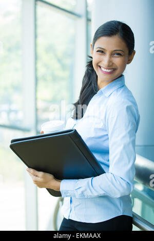 Closeup Portrait, junge professionelle, schöne selbstbewusste Frau im blauen Hemd, hält Kaffee und schwarzen Notizbuch Stockfoto