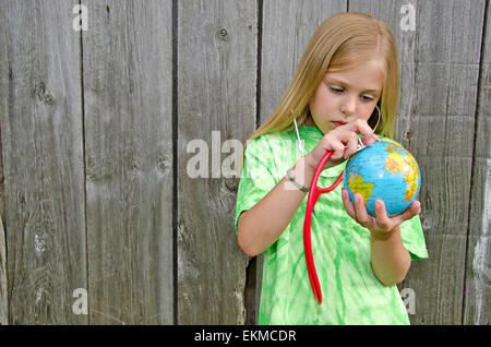 Kaukasische Mädchen mit Stethoskop auf eine Weltkugel in der Hand. Stockfoto