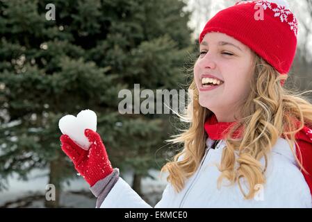 Junge lächelnde Teenager-Mädchen mit Eis-Herzen in der rote Handschuh. Stockfoto