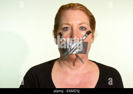 Zensur der Kunst oder Künstler, die von einer Frau mit Duct Tape und Farbe Pinsel über den Mund zum Ausdruck gebracht Stockfoto