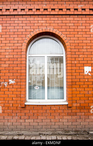 Weiß lackiertes gewölbtes Fenster in einer roten Backsteinmauer Stockfoto