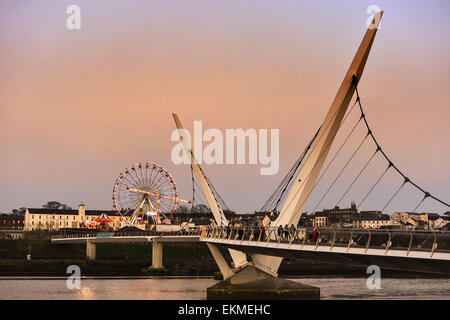 Peace Bridge in der Dämmerung mit Riesenrad im Hintergrund, Derry, Londonderry, Nordirland. Stockfoto