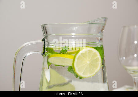 Stellplatz mit frischem Wasser mit Zitronenscheiben und Minzeblätter und einen Teil eines Glases im Hintergrund dekoriert Stockfoto