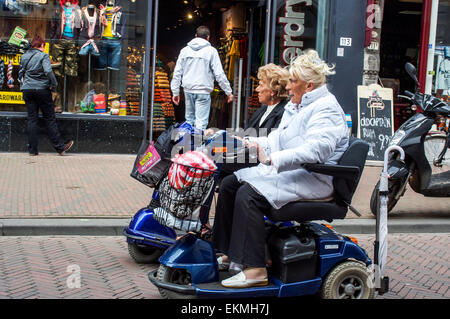 Ältere Zoomen Omas auf Scooter fahren Sie ziemlich schnell durch Fußgängerzone in Rotterdam, Niederlande. Stockfoto