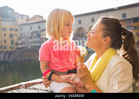 Glückliche Mutter und Babymädchen Essen ein Eis in der Nähe von Ponte Vecchio in Florenz, Italien Stockfoto