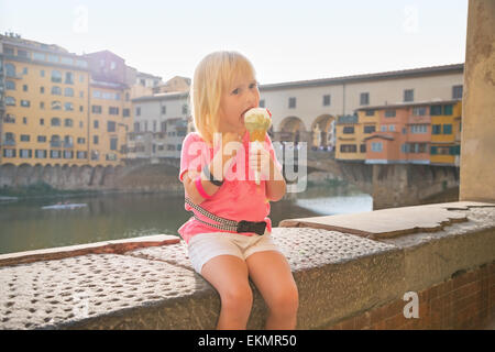 Porträt von glückliches Babymädchen Essen ein Eis in der Nähe von Ponte Vecchio in Florenz, Italien Stockfoto