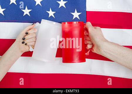 Schließen Sie herauf Bild der weiblichen und männlichen Hände halten große Plastik Becher mit Flagge der Vereinigten Staaten von Amerika zu trinken Stockfoto