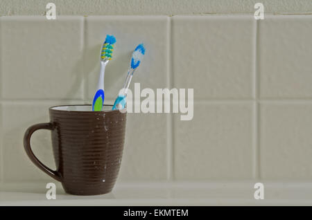 Zahnbürsten im Cup auf der Wand des Badezimmers verwendet Stockfoto