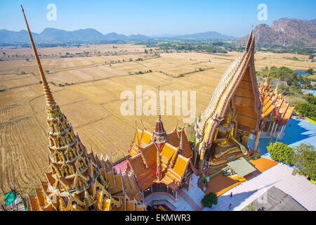 Ein Blick von oben auf die Pagode, goldene Buddha-Statue mit Reisfeldern und Bergen, Wat Tham Sua(Tiger Cave Temple), Tha Moun Stockfoto