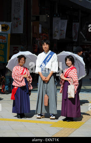 Junge japanische Werbe Menschen in traditionellen Kostümen gekleidet Förderung der Stadt Matsuyama, Japan. Kimono, Kimonos, Sonnenschirme, junger Mann, Frauen Stockfoto