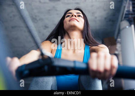 Lächelnde hübsche Frau am Simulator im Fitness-Studio trainieren Stockfoto