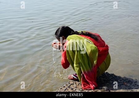 Ein indisch-hinduistischen Frau trinkt Wasser aus der hohlen Hand Narbada Shiva River Festival Madhya Pradesh, Indien Stockfoto