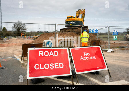 Straßenbauarbeiten, Straßensperrschild mit Bauarbeiten und Bauarbeitern, die eine neue Straße bauen, England, Großbritannien. Straßenblockschilder. Stockfoto