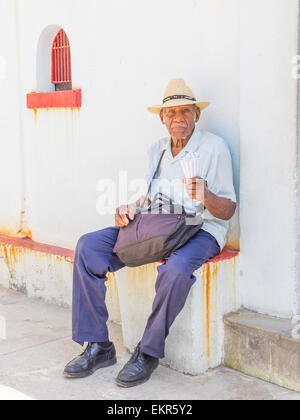 Kopf und Schultern Porträt eine männliche Afro-kubanischen Seniorin Erdnüsse in der traditionellen Papiertütchen in Strohhut zu verkaufen. Stockfoto