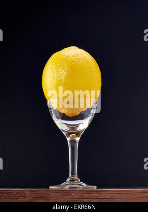 Ganze Zitrone in einem eleganten Glas auf schwarzem Hintergrund Stockfoto