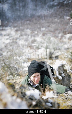 Ein Mann, Wandern in den Bergen klettern auf einer steilen Felswand. Stockfoto