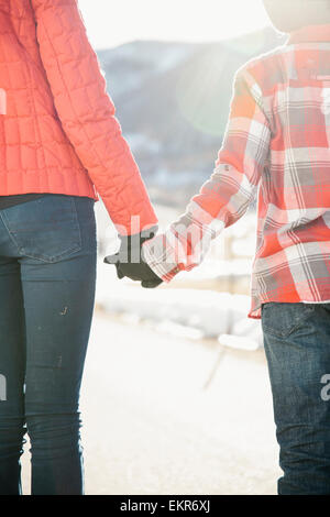 Zwei Kinder Hand in Hand mit Blick auf eine verschneite Winterlandschaft. Stockfoto